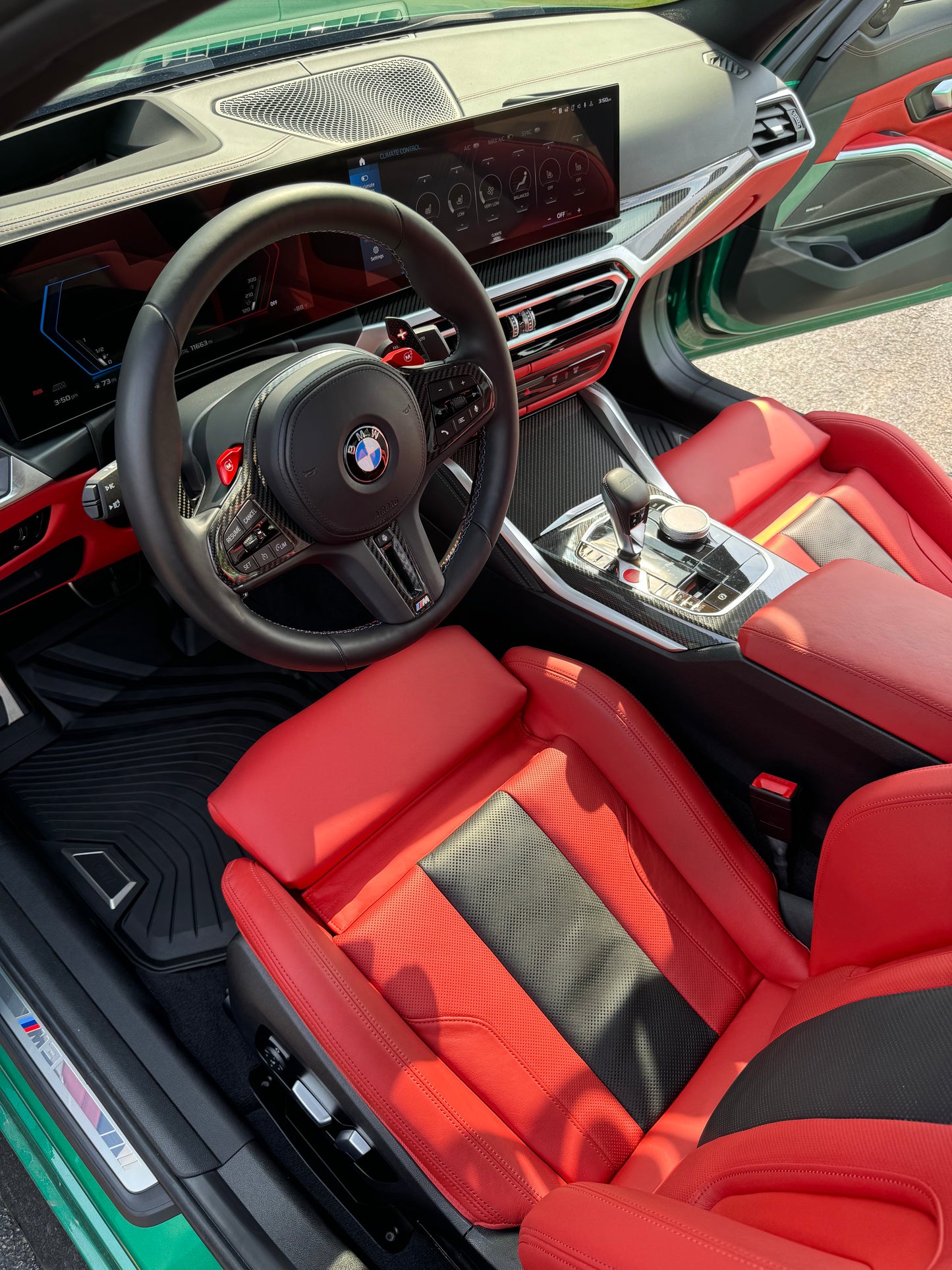 Car interior with red seats and steering wheel, featuring BMW logo.