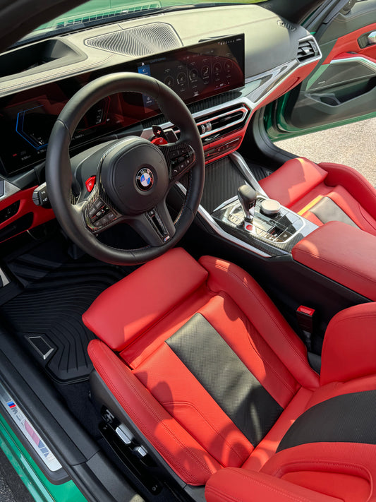 Car interior with red seats and steering wheel, featuring BMW logo.