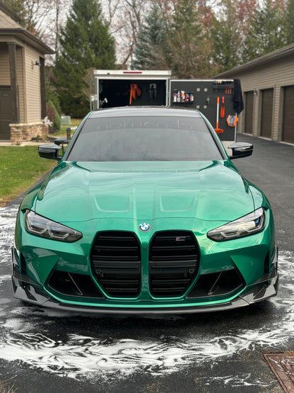 Freshly detailed green BMW with detailing trailer in background